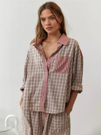 Voorkant van het beige roze geruite overhemd met roze gestreepte borstzak en knoopsluiting, model kijkt de camera in met handen in de zakken. 4