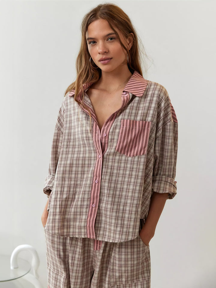 Voorkant van het beige roze geruite overhemd met roze gestreepte borstzak en knoopsluiting, model kijkt de camera in met handen in de zakken. 4