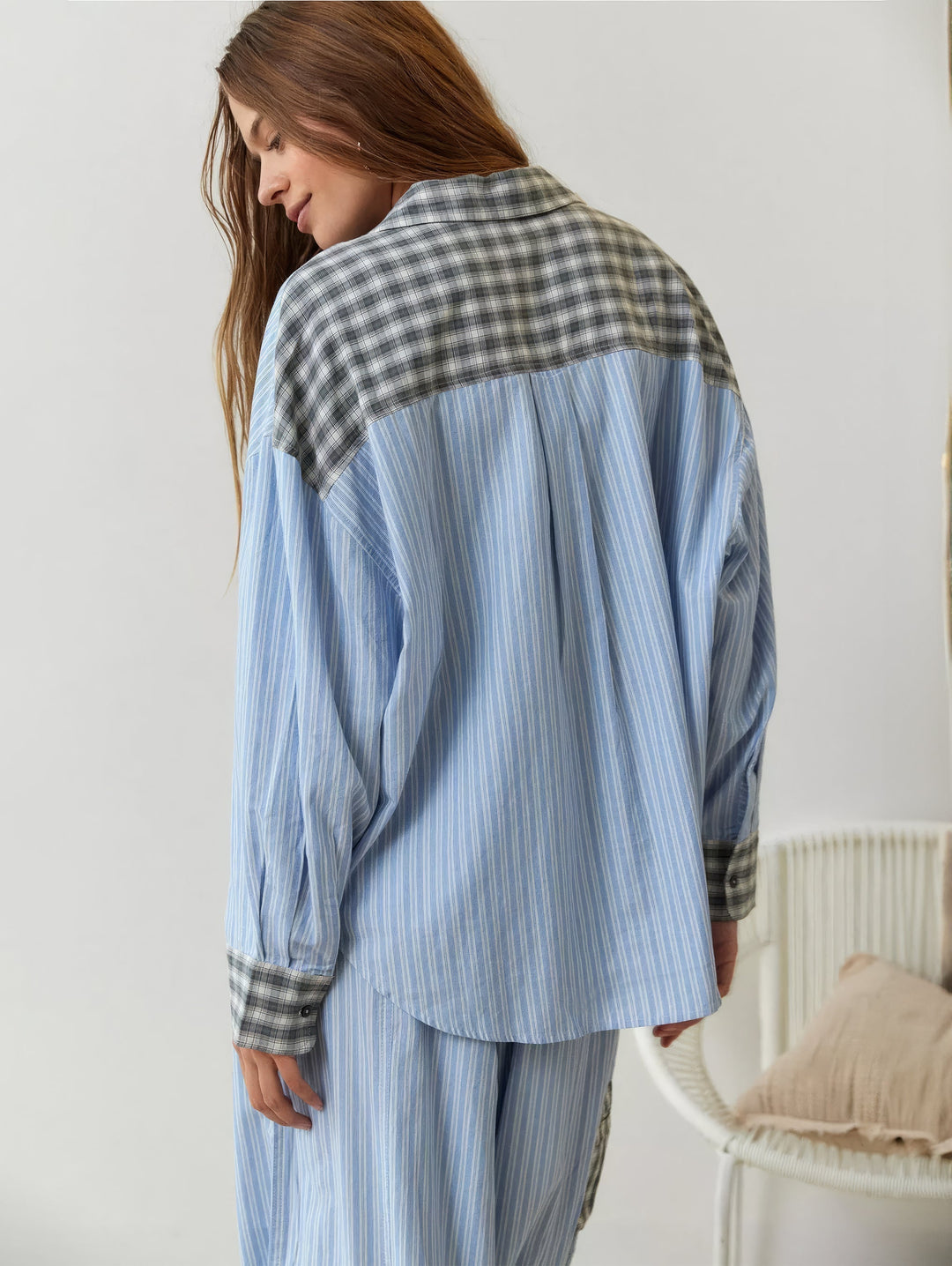 Achterkant van het blauw gestreepte overhemd met grijs geruite schouderpas en manchetten, model kijkt over haar schouder naar beneden. 9