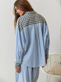 Achterkant van het blauw gestreepte overhemd met grijs geruite schouderpas en manchetten, model kijkt over haar schouder naar beneden. 9