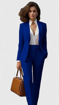 Model draagt het kostuum in kobaltblauw met een witte blouse en een bruine handtas. 6