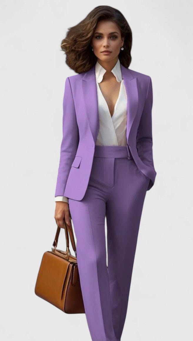 Model draagt het kostuum in lila, met witte blouse en een bruine leren handtas in de hand. 9