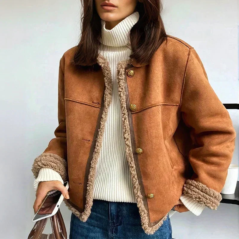 Model draagt de bruine jack open over een witte coltrui en spijkerbroek, met een tas in de hand 1