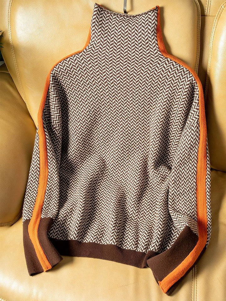 Bruin-beige trui met visgraatpatroon en oranje zijstrepen plat uitgespreid op een leren bank, met bruine boord en manchetten. 4