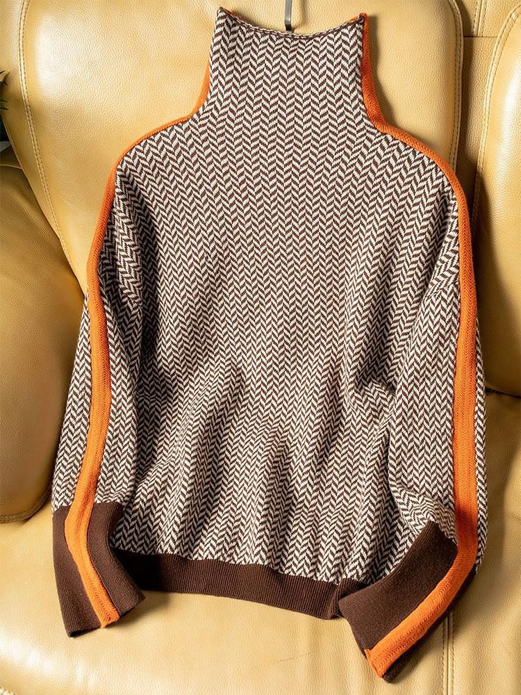 Bruin-beige trui met visgraatpatroon en oranje zijstrepen plat uitgespreid op een leren bank, met bruine boord en manchetten. 4
