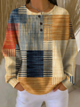 Wafeltrui met knoopjes en blokpatroon met strepen in blauw, oranje, rood en beige, gedragen met witte broek. 3