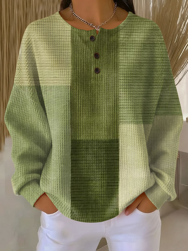 Wafeltrui met knoopjes in groene tinten met kleurvlakken, gedragen door een model met witte broek. 4