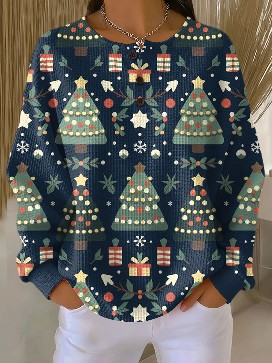 Donkerblauwe wafeltrui met knoopjes en print van kerstbomen, cadeautjes en sterren, gedragen door een model. 8