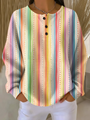 Wafeltrui met knoopjes en verticale regenboogstrepen met stippellijnen in vrolijke kleuren, gedragen met witte broek. 10
