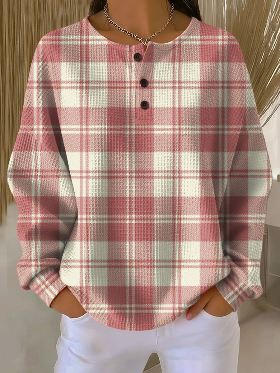Wafeltrui met knoopjes en roze-witte ruitprint, gedragen door een model met handen in de zakken. 15