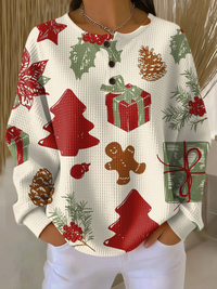 Crèmekleurige wafeltrui met knoopjes en kerstprint van rode kerstbomen, cadeaus, peperkoekmannetje, dennenappels en hulstbladeren, gedragen door een model. 23
