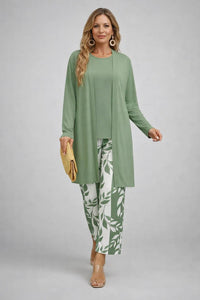 Model in lichtgroen vest en top met broek met groen-witte bladprint, gele clutch en doorzichtige sandalen. 10