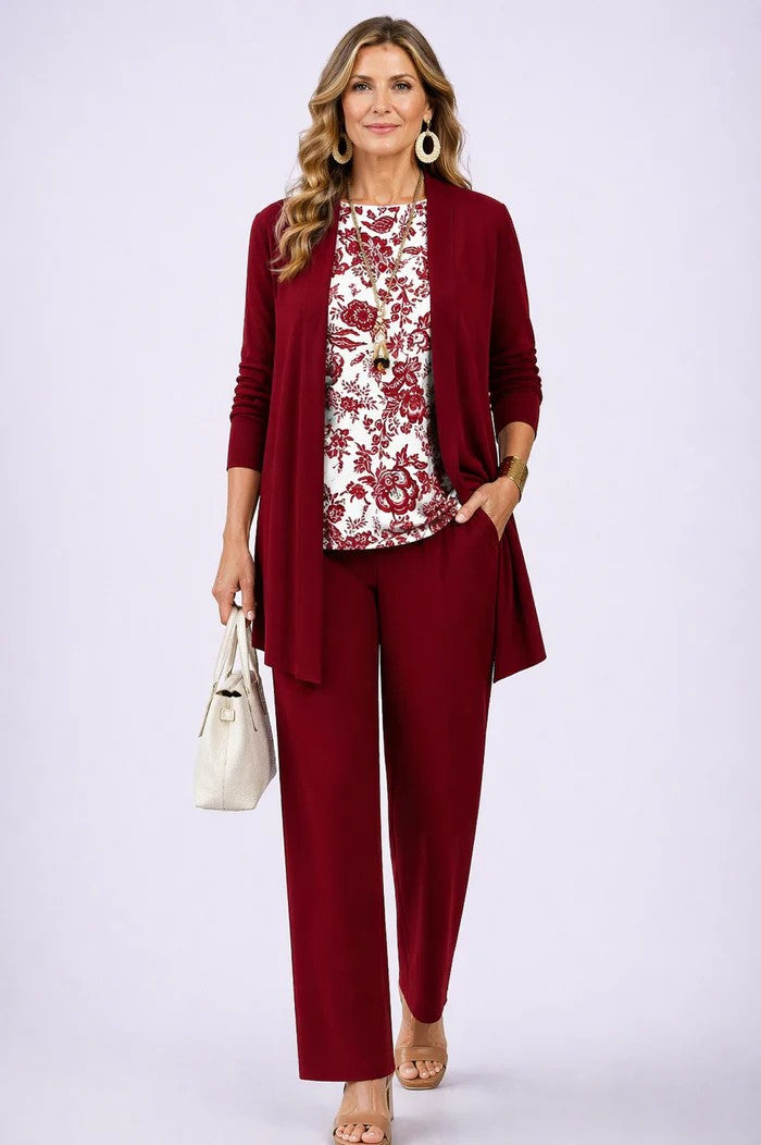 Model in rood open vest en broek met witte top met rode bloemenprint, beige handtas in de hand. 13