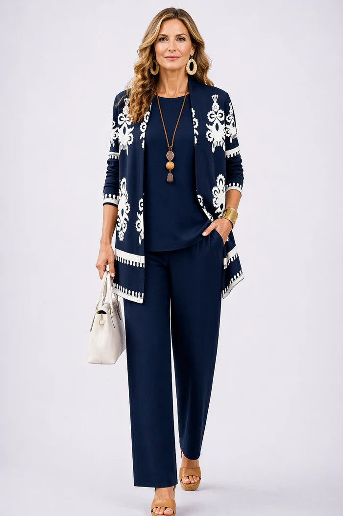 Model in marineblauwe set met vest met witte ornamentprint, effen top en broek, hand in de zak. 14