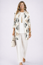 Model in witte set met zwarte en beige bladprint op het open vest, effen witte top en broek. 4