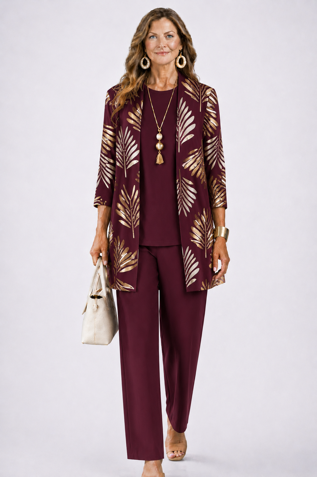 Model in bordeauxrode set met gouden bladprint op het open vest, effen top en rechte broek. 6