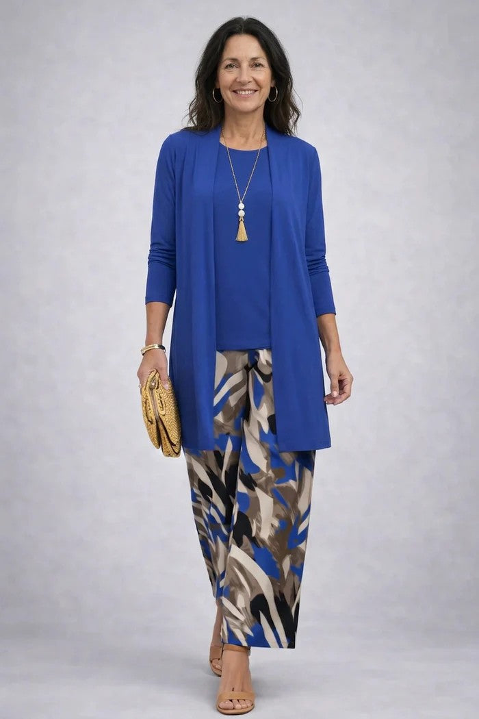 Model in effen blauw lang vest en top, gecombineerd met broek met abstracte blauw-bruine print en strogele clutch. 9
