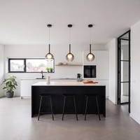Drie rookgrijze glazen globelampen met zwarte steel boven een kookeiland in een moderne witte keuken 1