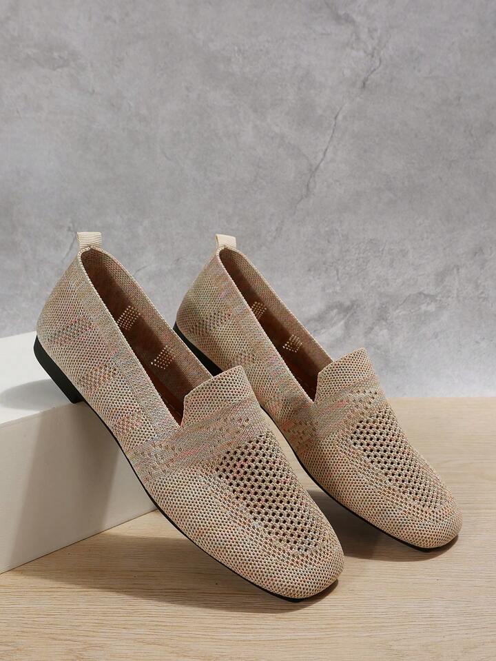 Beige gebreide instappers met gaatjesmesh, een schoen leunend tegen een wit blok voor een grijze muur. 7