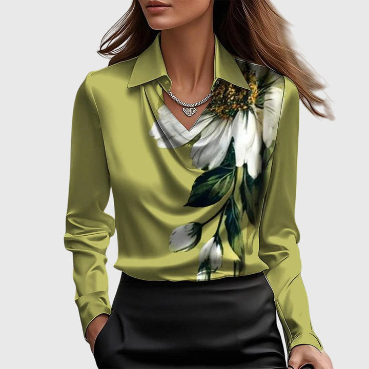 Model draagt de groene satijnen blouse met een grote witte bloemprint met bladeren op de borst, gecombineerd met een zwarte rok. 7
