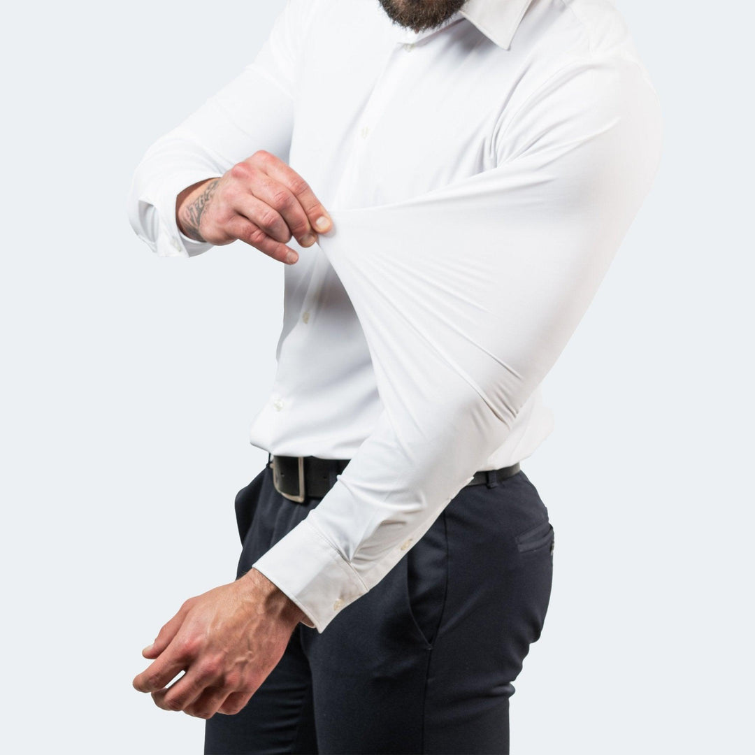 Man in wit overhemd en donkerblauwe broek trekt de mouw bij de elleboog uit om de rekbaarheid van de stof te tonen. 4