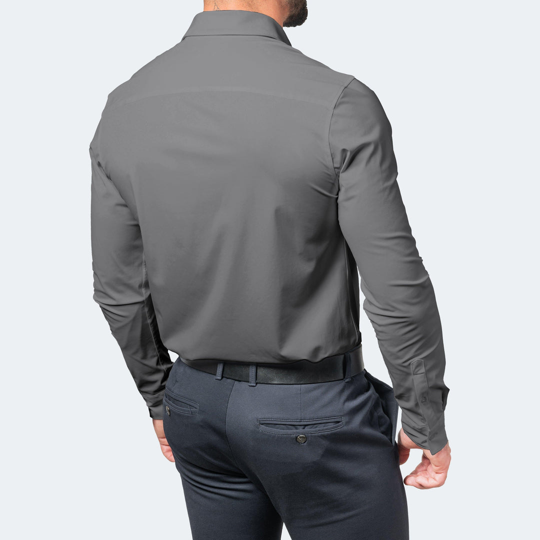 Achterkant van een grijs overhemd met lange mouwen, gedragen door een man in een donkerblauwe pantalon met zwarte riem. 6