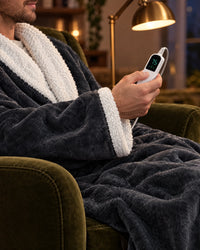 Man in een fauteuil in de grijze jas houdt de witte bedieningsunit met digitaal display vast, de witte kraag en manchet zichtbaar. 6