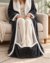 Close-up van iemand op een bank met de benen in de voetenzak van de jas, bekleed met witte sherpa. 5