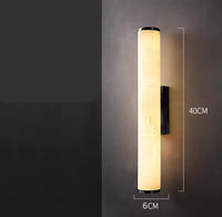 Verlichte cilindrische marmeren wandlamp tegen een donkere muur, met maataanduiding van 40 cm hoog en 6 cm breed. 22