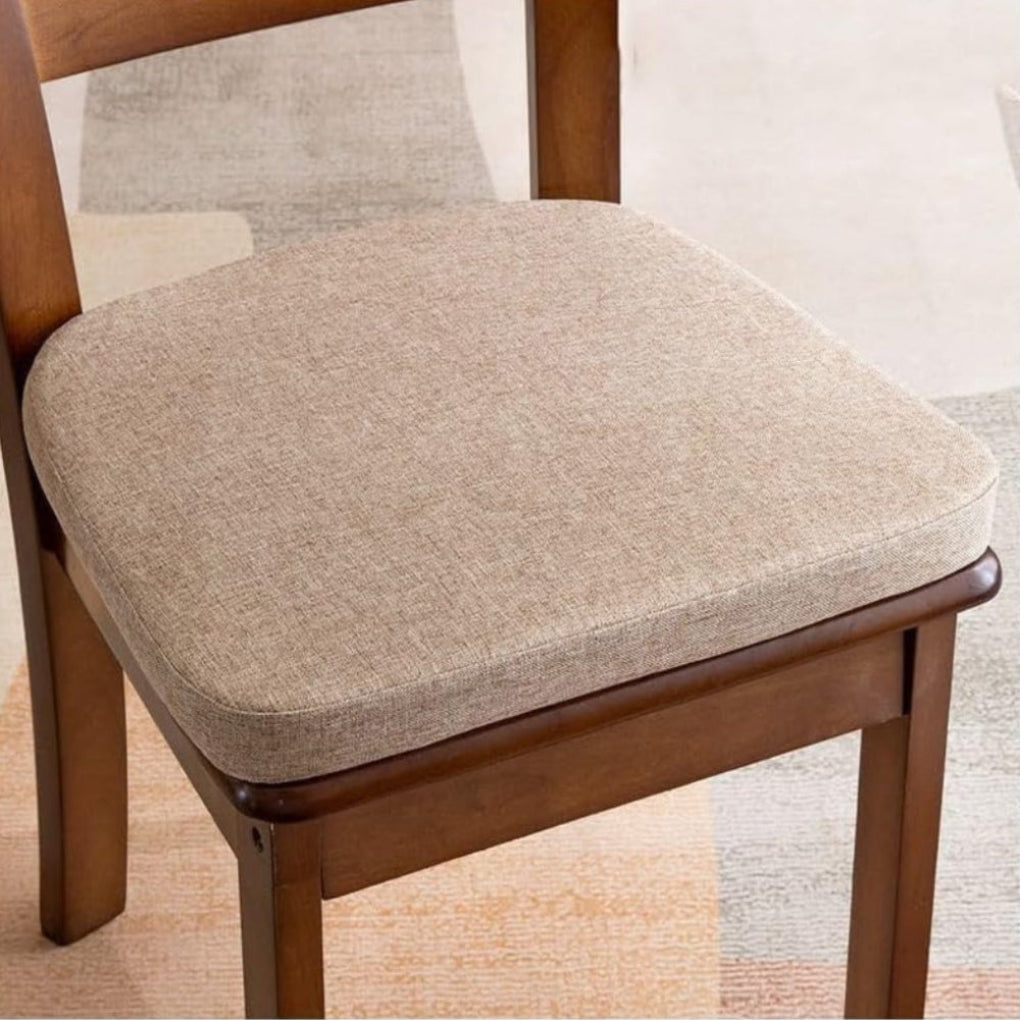Beige zitkussen met fijne stofstructuur op een houten stoel naast een gestreept tapijt 5