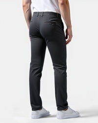 Achterkant van de donkergrijze chino met paspelzakken, gedragen met wit shirt en witte sneakers. 8