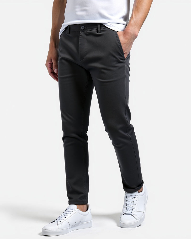 Donkergrijze slim fit chino van opzij, gedragen met wit shirt en witte sneakers, een hand in de zak. 6