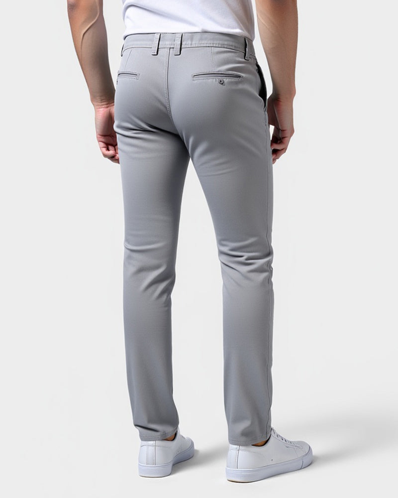 Achterkant van de lichtgrijze chino met twee paspelzakken achter, gedragen door een model met witte sneakers. 3