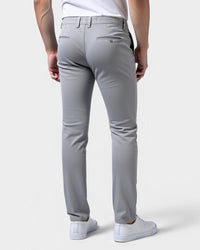 Achterkant van de lichtgrijze chino met twee paspelzakken achter, gedragen door een model met witte sneakers. 3