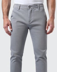 Close-up van de taille van de lichtgrijze chino met knoop, gulp en riemlussen, model heeft handen langs het lichaam. 5