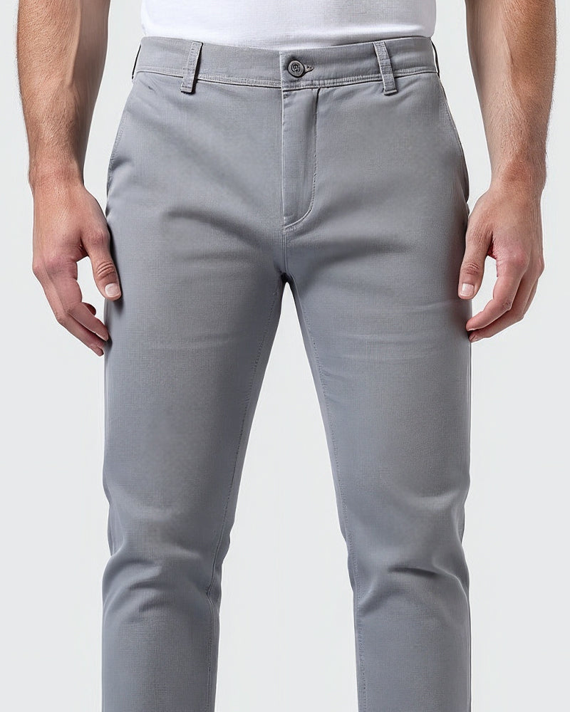 Close-up van de taille van de lichtgrijze chino met knoop, gulp en riemlussen, model heeft handen langs het lichaam. 5