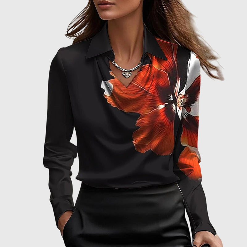 Model draagt de zwarte satijnen blouse met een grote oranjerode bloemprint over de schouder en borst, gecombineerd met een zwarte rok. 6