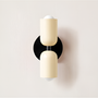 Wandlamp met twee crèmekleurige lampkoppen op een zwarte ronde wandplaat. 36