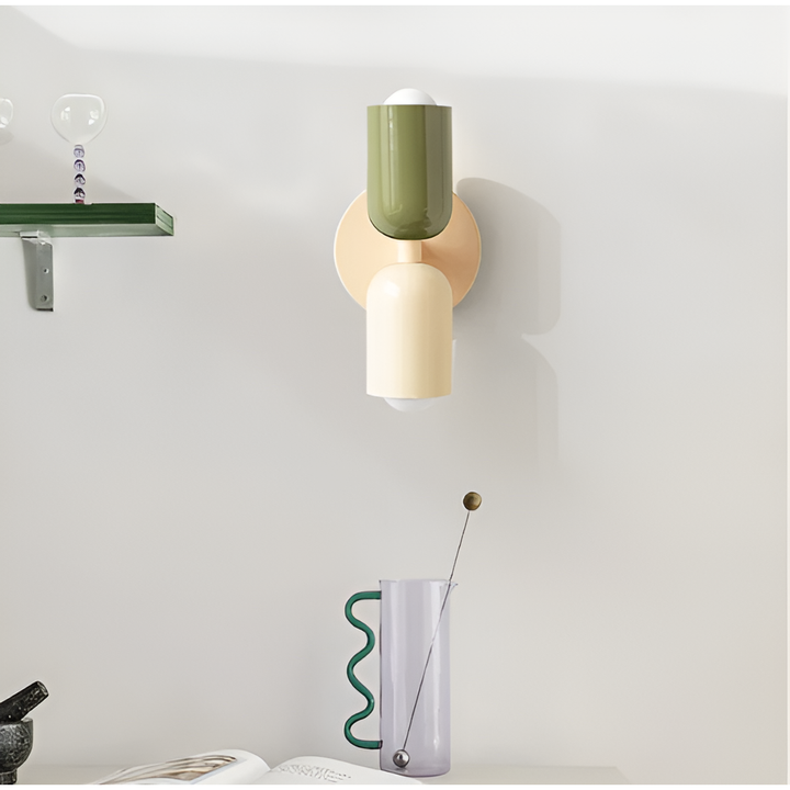 Wandlamp met groene bovenkap en crèmekleurige onderkap aan de muur, naast een plank en een glazen karaf. 35