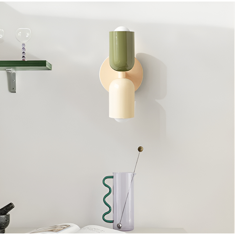 Wandlamp met groene bovenkap en crèmekleurige onderkap aan de muur, naast een plank en een glazen karaf. 35