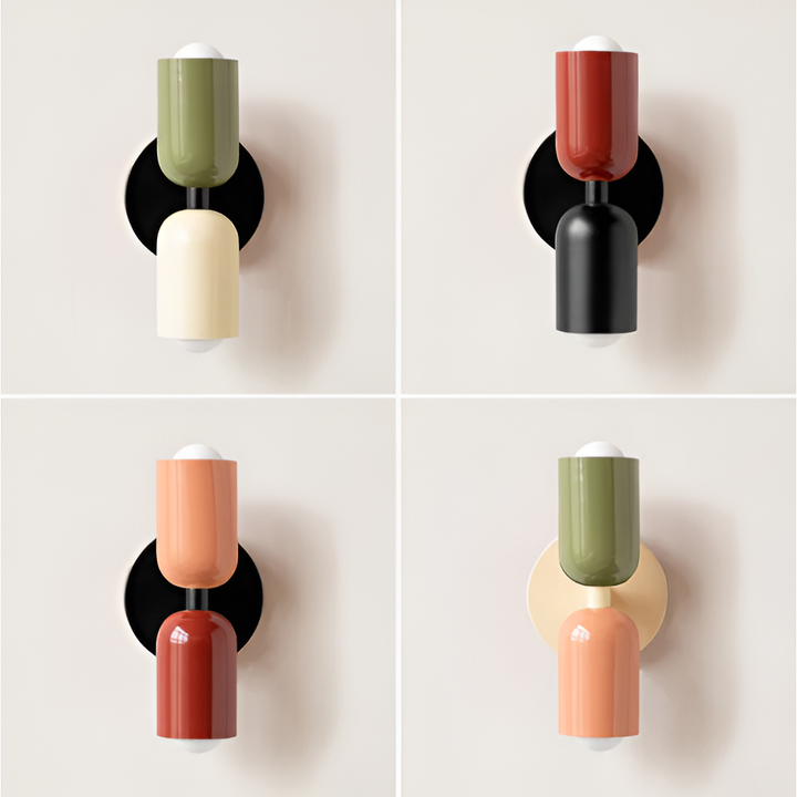 Collage van vier wandlampen met twee lampkoppen in verschillende kleurcombinaties van groen, crème, rood, zwart en perzik op een lichte muur. 1