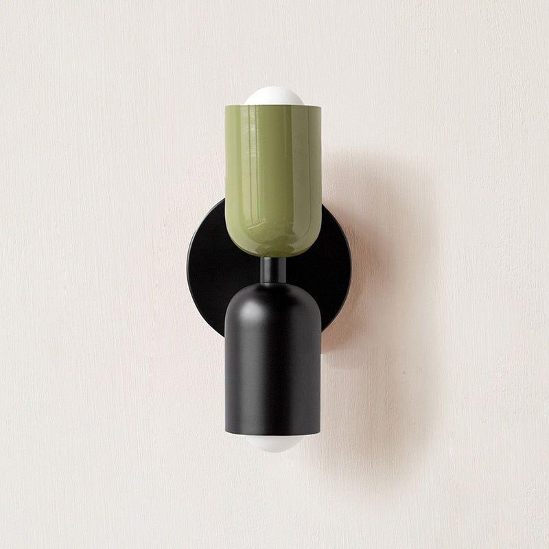 Wandlamp met een groene bovenste kop en een mat zwarte onderste kop op een ronde zwarte muurplaat. 12