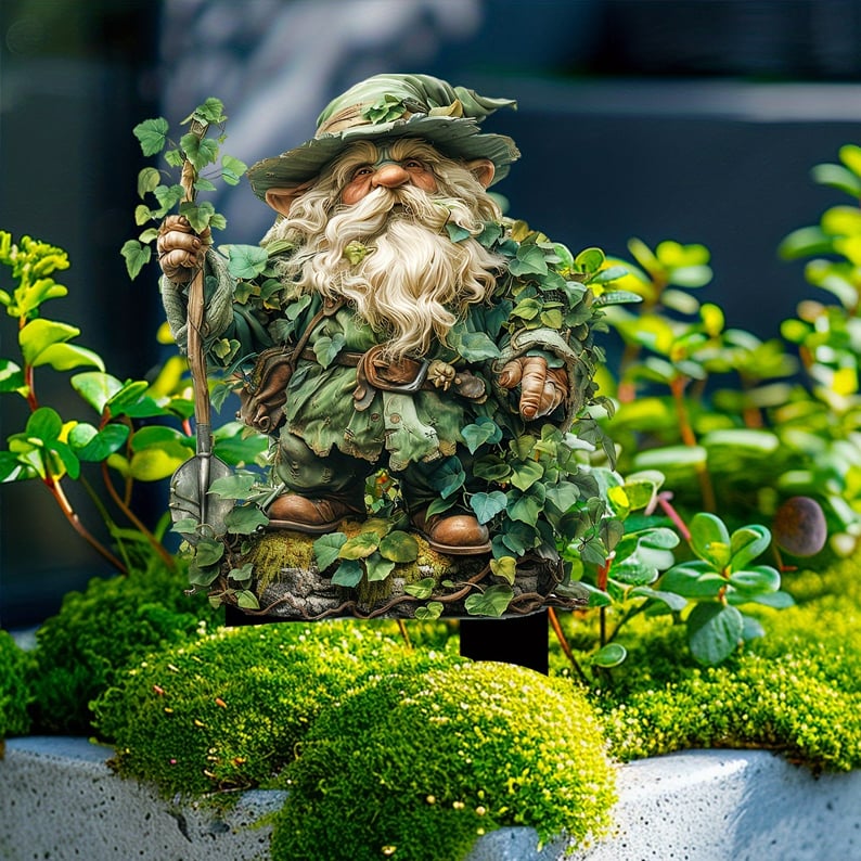Tuinprikker van de kabouter met blaadjeshoed en schep, geplaatst op mos in een plantenbak met groene planten. 13