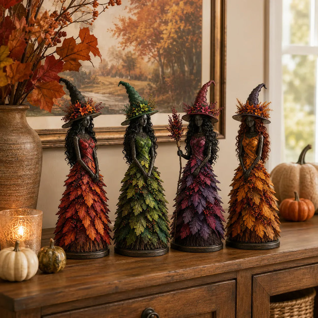 Rij van vier heksbeeldjes in rood, groen, paars en geel op een houten dressoir voor een herfstschilderij. 7
