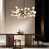 Verlichte takkenlamp boven een donkere ovale eettafel met leren stoelen en decoratieve vazen 5