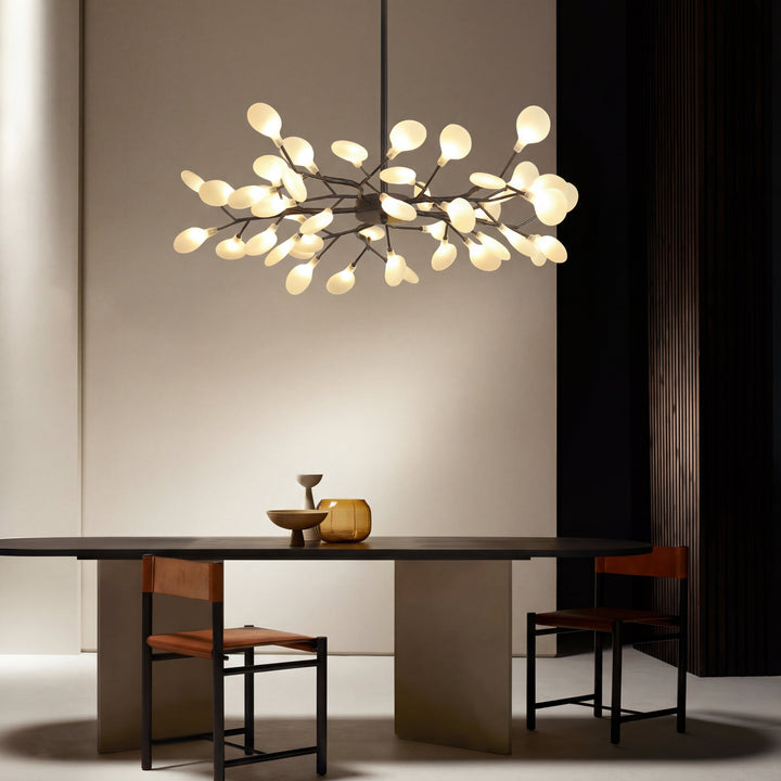 Verlichte takkenlamp boven een donkere ovale eettafel met leren stoelen en decoratieve vazen 5