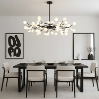 Zwarte takkenlamp boven een zwarte eettafel in een lichte, minimalistische eetkamer met grafisch schilderij 2