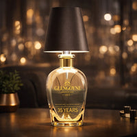 Donkerbruine lampenkap op een heldere glazen whiskyfles met gouden hals, tegen een glinsterende achtergrond 13