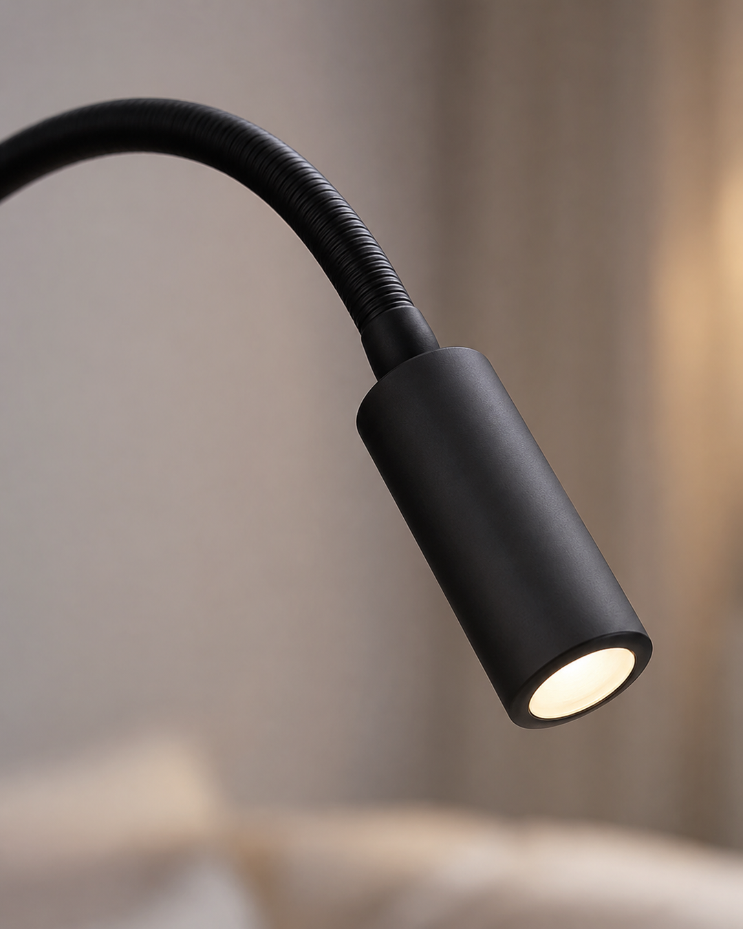 Close-up van de zwarte lampkop met geribbelde, buigzame hals en een warm brandend ledlicht, tegen een zacht wazige achtergrond. 4