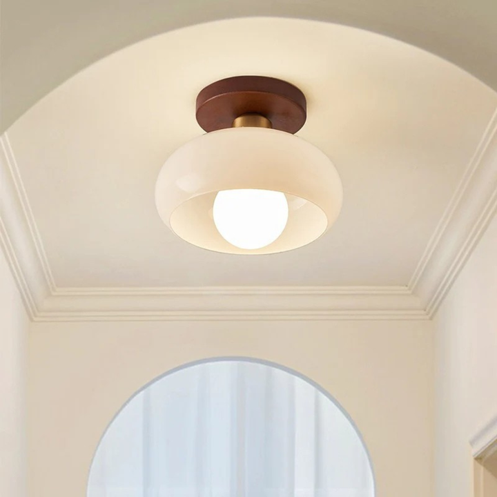 Lichtgevende lamp met gouden verbindingsstuk aan een gewelfd plafond met sierlijst in een gang 3